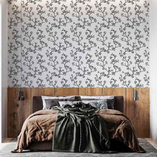 Black and white wallpaper with slim branches and delicate floral sprigs